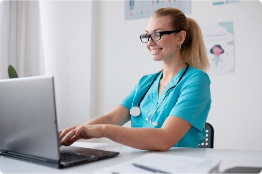 Smiling female medical biller or coder using a laptop for Gastroenterology Billing Services