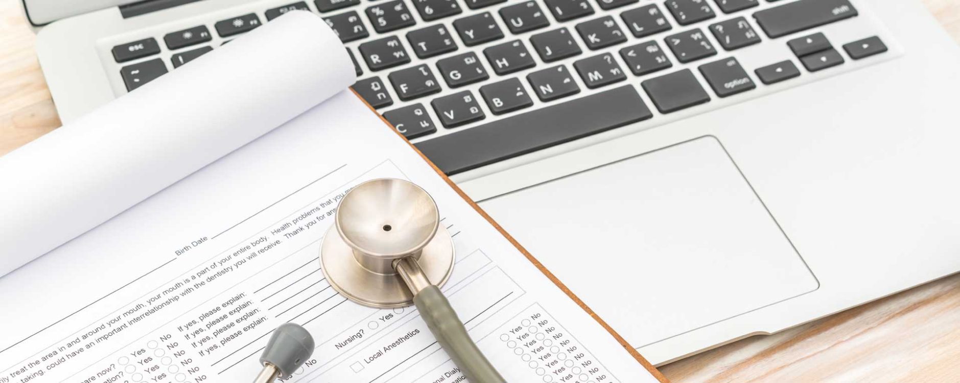 Stethoscope on medical form beside a laptop, representing top medical billing companies in Miami, Florida.
